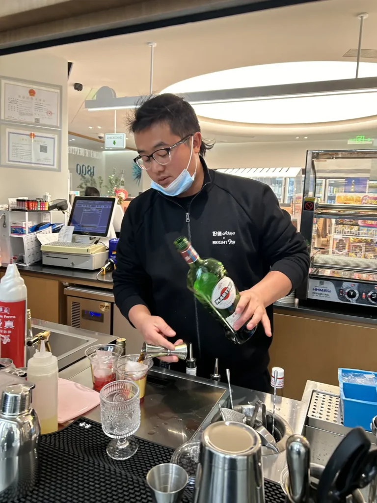 A barman mixing a Negroni cocktail at a convenience store counter in Shanghai