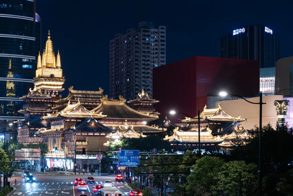 Jing'an Temple illuminated at night, surrounded by Shanghai's modern skyline