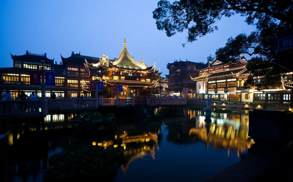 Yu Gardens bazaar illuminated at night, reflected in the surrounding pond, Shanghai