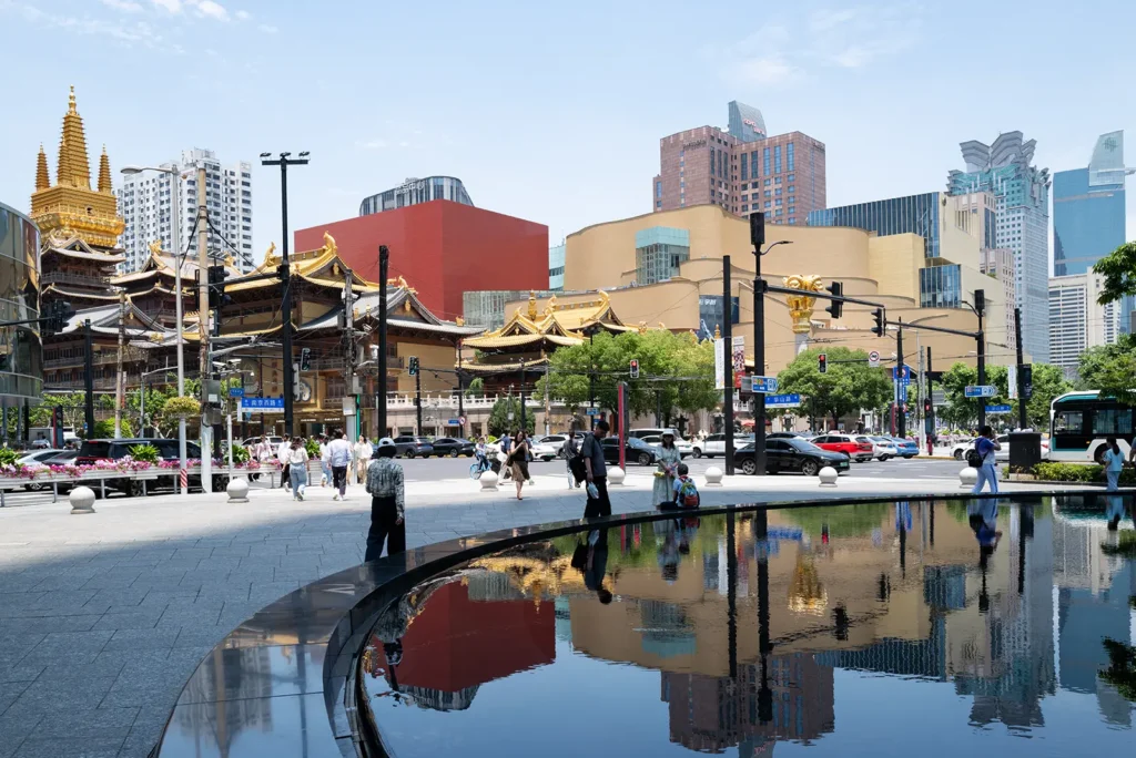 Jing'an Temple reflected in the plaza water feature, with luxury malls and modern Shanghai skyline behind