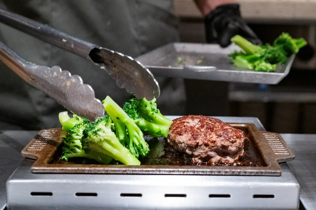 Freshly cooked burger on a personalised grill with a side of broccoli
